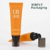 Orange PE cosmetic airless pump tube with clear cap for sunscreen and lotion